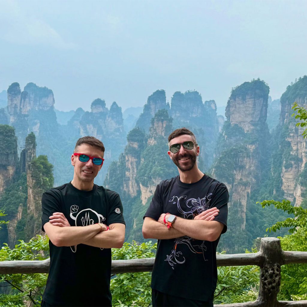 Christopher and Jesse of Borderless Bros Club standing in front of dramatic mountain spires in China, sharing their mission of bold, inclusive travel.