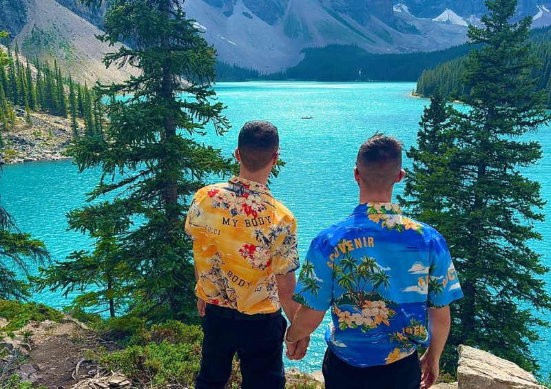 Christopher and Jesse from Borderless Bros Club pose in front of the turquoise waters and majestic peaks of Moraine Lake in Banff National Park, Canada — showcasing nature, style, and fearless travel.