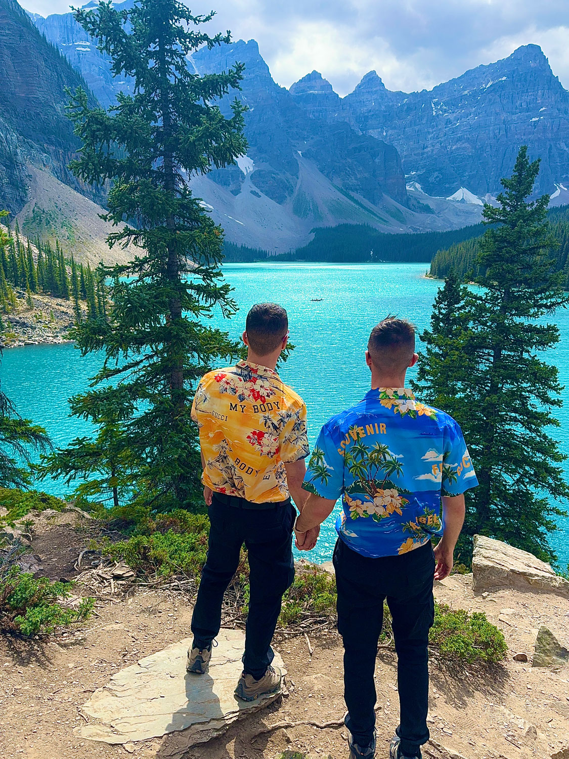 Christopher and Jesse from Borderless Bros Club pose in front of the turquoise waters and majestic peaks of Moraine Lake in Banff National Park, Canada — showcasing nature, style, and fearless travel.